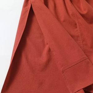 Detailed close-up of woven fabric texture and side slit on a burnt orange summer dress