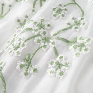 Gros plan détaillé du tissu en dentelle blanche avec tiges vertes et broderie marguerite
