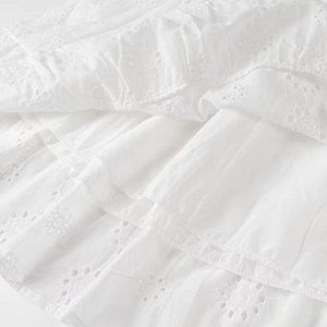 Close-up of white eyelet embroidery cotton fabric with intricate floral cutout details
