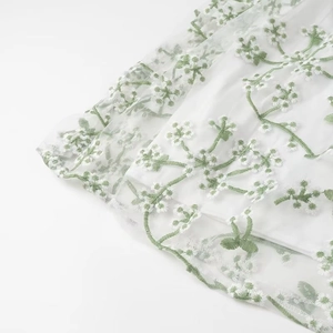 Détail de la broderie florale et des couches de mesh sur la robe longue blanche élégante