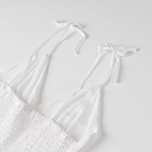 Detailed close-up of white summer dress with smocked bodice and delicate tie straps