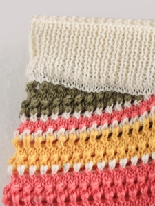 Detailed close-up of multi-color striped crochet knit fabric showing texture and stitches