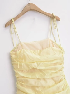 Detail of light yellow midi dress with pleated texture and adjustable tie straps