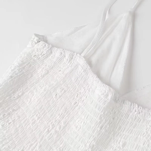 Close-up of white dress detailing smocking texture and fine shirring embroidery