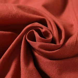 Detail of rust red cotton-linen fabric with neat double-needle stitching and texture