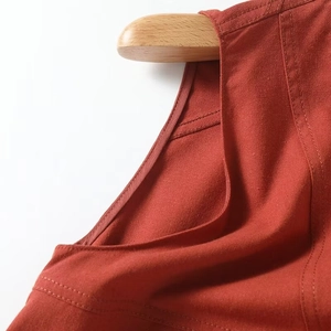 Close-up of V-neckline and shoulder seams on terracotta linen dress with twin-needle stitching