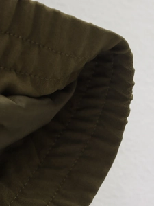 Détail du poignet élastique vert armée montrant la texture tissée de haute qualité et les coutures