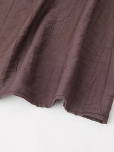 Detailed macro view of dark brown textured fabric with striped grain and fine hem stitching