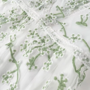 Détail du tissu en maille blanche avec broderies florales et bords en dentelle élégants