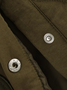Gros plan des boutons-pression argentés étoilés sur veste brodée vert armée