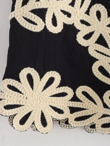 Vue macro des appliques florales au crochet et broderies blanches sur haut noir