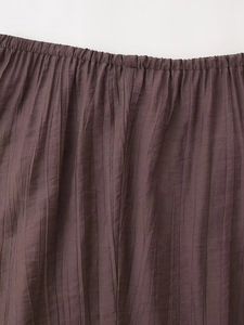 Macro shot of dark brown pleated skirt featuring elastic waistband and vertical texture