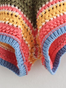 Macro view of colorful striped crochet knit fabric showing detailed hollow patterns and ribbed edge