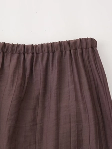Close-up of high-waist elastic band and pleated texture on dark brown summer skirt