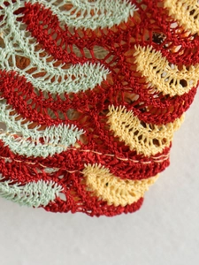 Detailed close-up of color-block crochet dress showing leaf-shaped hollow knit pattern