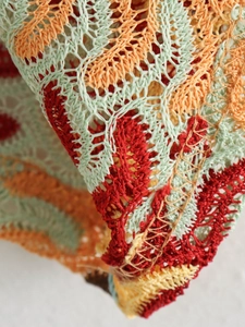 Detail of colorful hollow crochet fabric with orange and mint green knit patterns