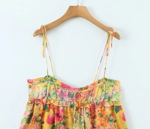 Detailed close-up of yellow floral sundress featuring lace-up straps and ruffled neckline