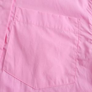 Detail shot of the front chest pocket and fabric texture on a pink short sleeve shirt