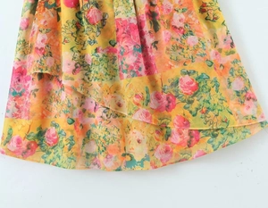 Detail of floral summer dress featuring yellow patchwork pattern and layered ruffle hem