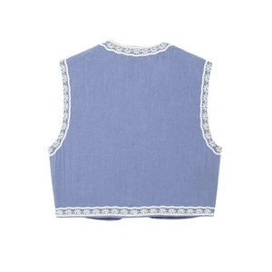 Détail du gilet court bleu avec broderies blanches ethniques et bordures ondulées