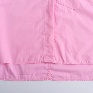 Detail view of pink cotton shirt featuring precise stitching and irregular hemline