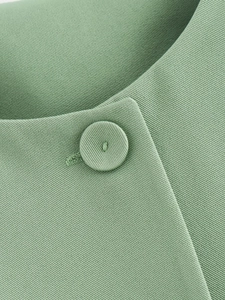 Macro de tissu sergé vert sauge avec des boutons recouverts de tissu assorti et coutures fines
