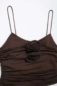 Detailed macro shot of 3D rose flowers and pleated fabric on brown camisole top