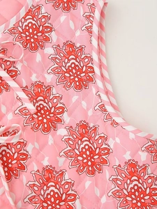 Detailed macro view of pink floral quilted fabric with diamond stitching and striped piping