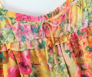 Detail of ruffled neckline and drawstring bow on yellow floral summer dress fabric