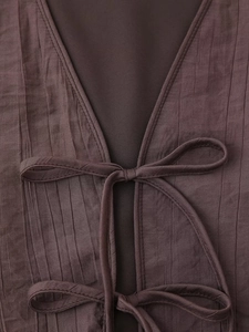 Detailed macro view of dark brown crinkle fabric with V-neckline and tie-up bow closure