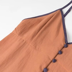Detail of V-neckline with contrast trim and fabric buttons on caramel summer dress