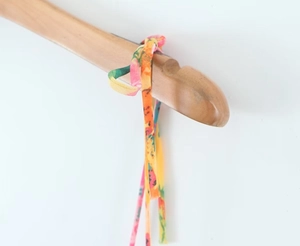 Detail of vibrant floral print fabric tie on a summer dress with refined rolled edges
