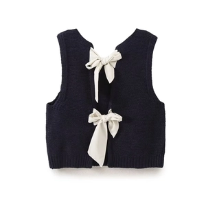 Détails de la veste en tricot bleu marine avec deux nœuds en satin et ourlet côtelé