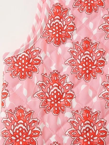 Macro view of pink floral quilted fabric with diamond stitching and striped piping details