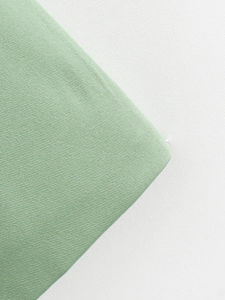 Gros plan sur la texture du tissu tissé vert clair avec une finition raffinée et précise