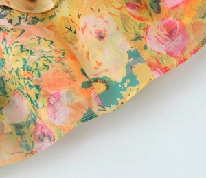 Detail shot of summer floral dress showing pink rose patterns on orange chiffon fabric