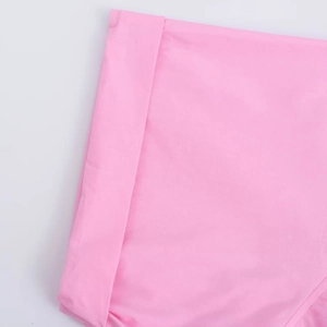 Detailed view of pink short-sleeve shirt fabric showing precise stitching and hem finish