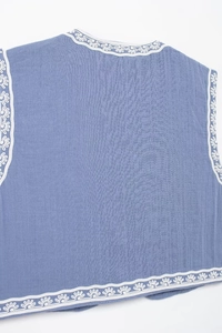 Détail d'un haut bleu sans manches avec broderie florale blanche et texture tissée