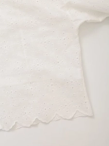 Close-up of white eyelet embroidery and scalloped edge detail on cotton blouse