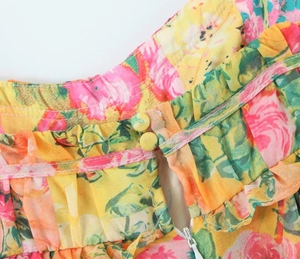 Detail of floral dress showing double yellow buttons, cutout back, and invisible zipper