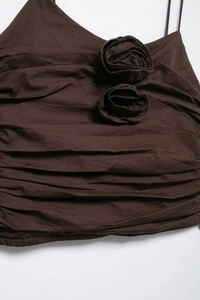 Detail of dark brown ruched fabric with 3D floral accents and delicate straps