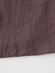Detail shot of the deep purple pleated fabric texture with elegant vertical accordion folds
