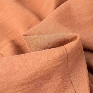 Close-up of brick red woven fabric texture with detailed linen-like fibers and fold