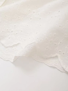 Detail of white cotton eyelet embroidery fabric with delicate scalloped lace edges