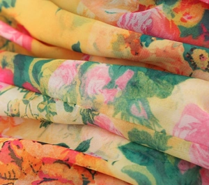 Close-up of lightweight floral fabric with vibrant yellow, pink, and orange patterns