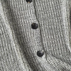 Close-up of chunky knit gray cardigan featuring textured marble-patterned brown buttons