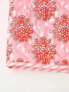 Detail of pink floral quilted fabric with red lotus pattern and striped binding trim