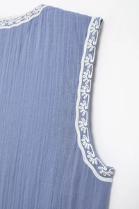 Vue détaillée du tissu en crêpe bleu avec broderie festonnée blanche sur les bords
