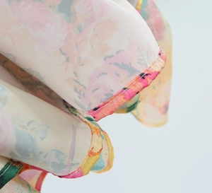 Macro detail of floral chiffon fabric with delicate pink blooms and neat rolled hem edges