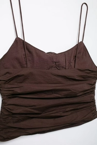 Detail of dark brown camisole showing pleated texture and slim spaghetti straps